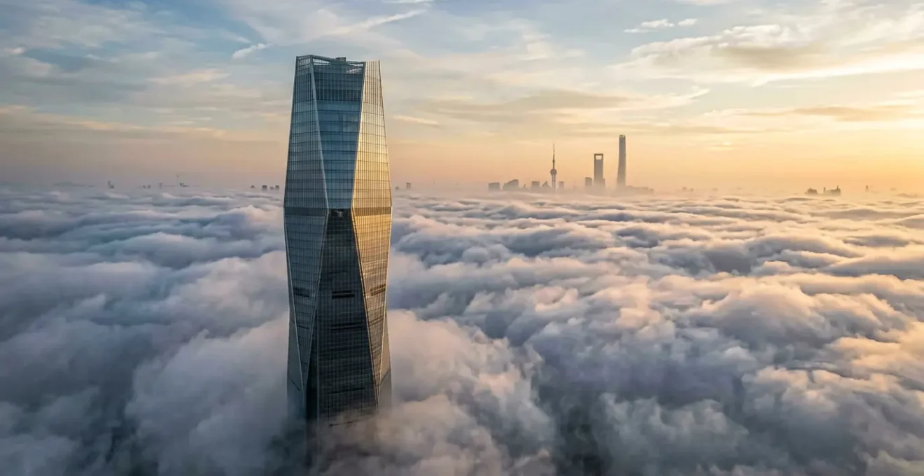 Vue aérienne d'une tour moderne émergeant des nuages avec Shanghai en arrière-plan