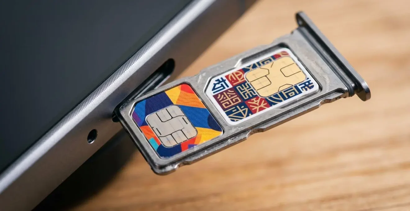 Main tenant un smartphone moderne montrant deux emplacements SIM avec des cartes de différents opérateurs